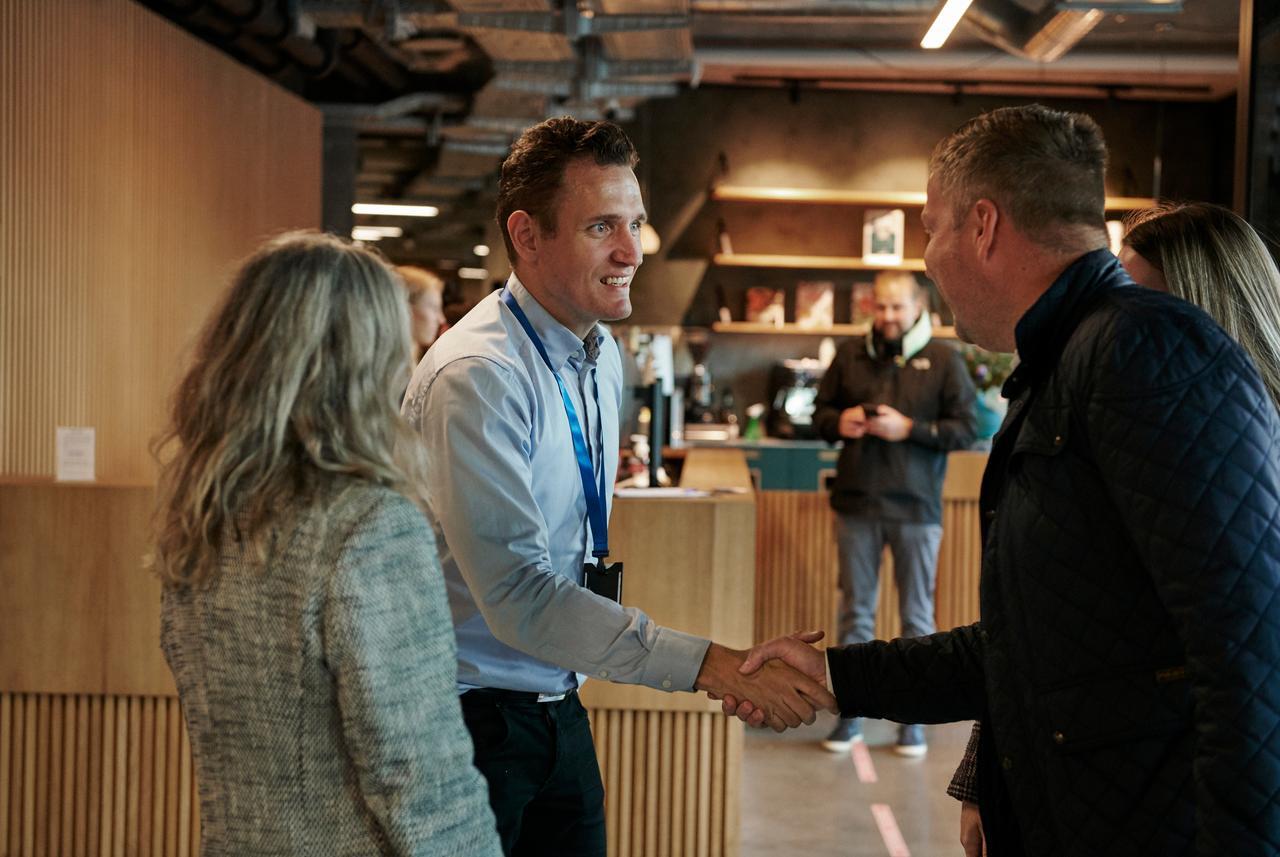 Visma-een hand geeft en glimlacht.