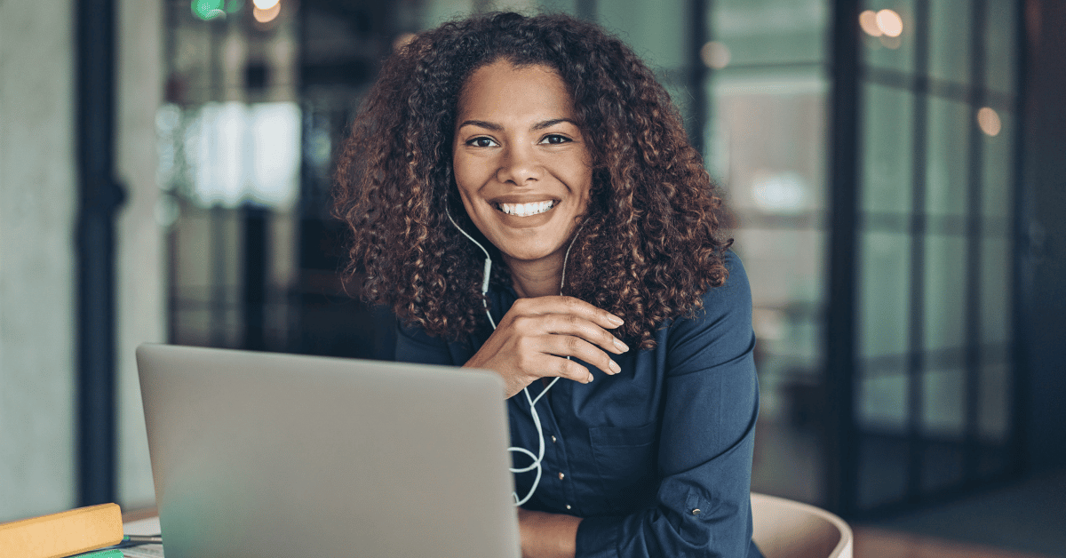 vrouw lachend achter haar laptop met headphones
