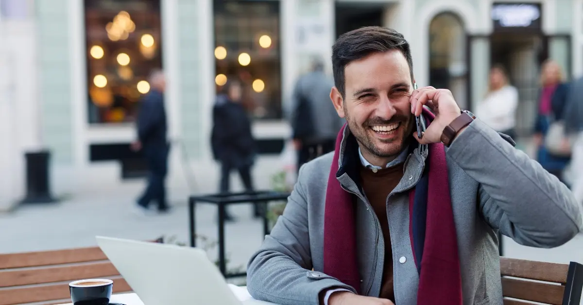 man aan de telefoon lacht en zit buiten