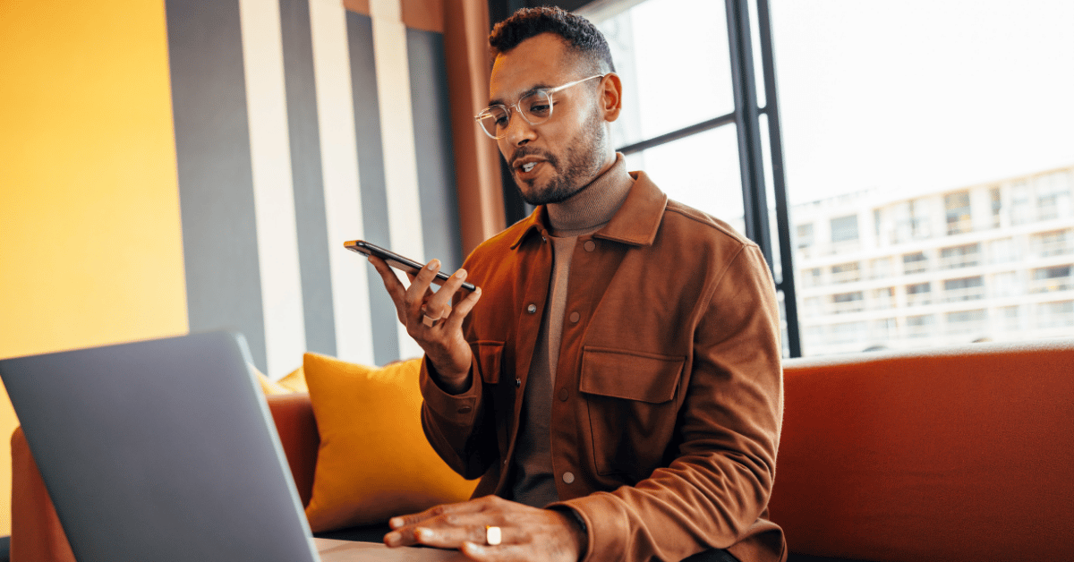 man zit achter laptop en belt handsfree