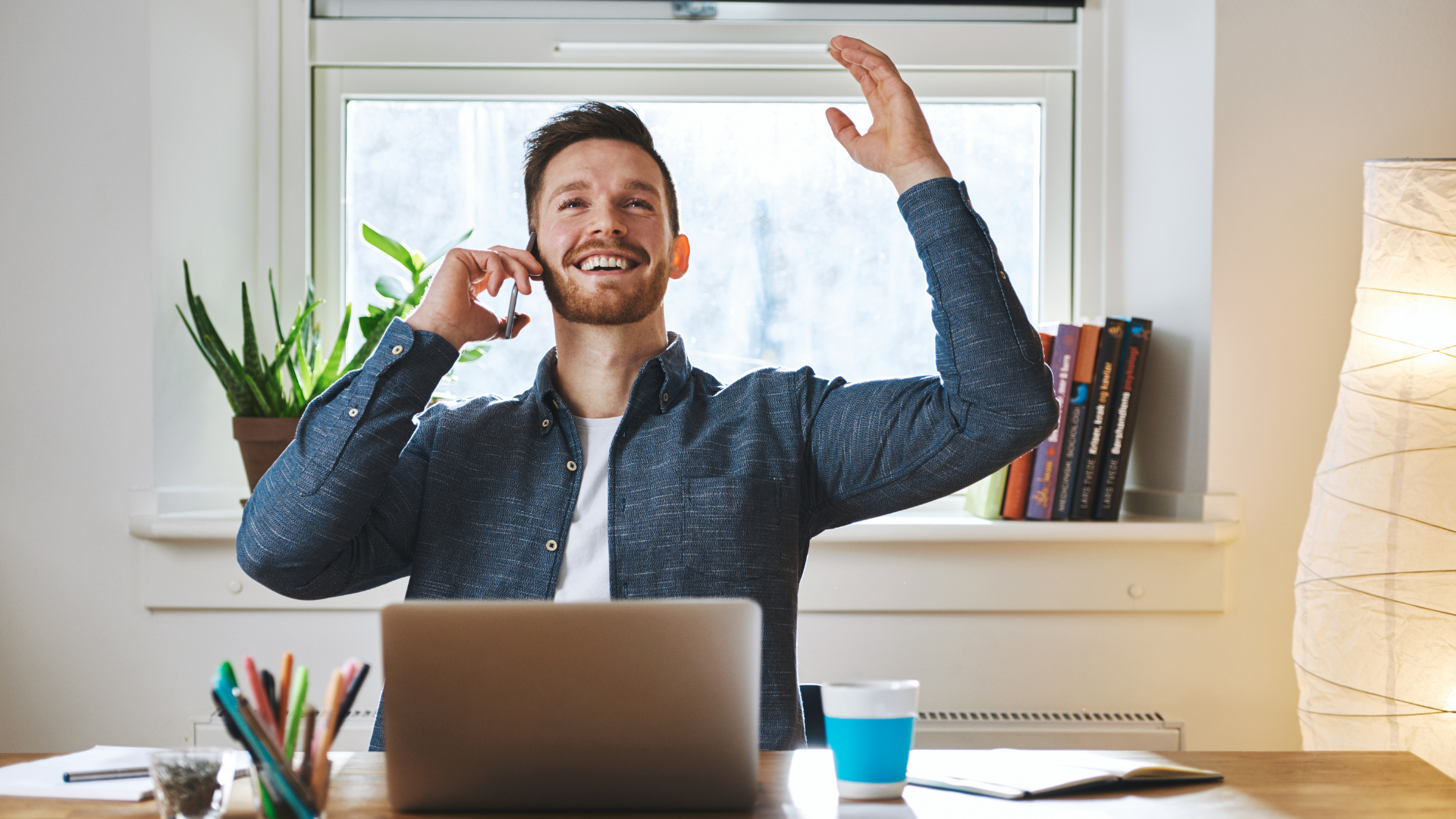 blije man met telefoon achter laptop